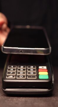 Close up of a person using a mobile phone to make a wireless payment on a pos terminal. Secure nfc technology for fast transactions