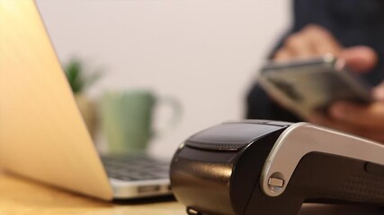 Customer securely paying with a smartphone using contactless nfc technology. A close up of a person tapping their mobile device on a pos terminal - Powered by Adobe