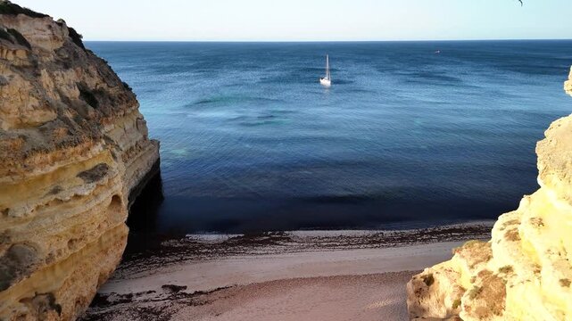 Scenic cliffs and azure sea near Praia do Camilo in Lagos Portugal during daytime with a sailboat on the water