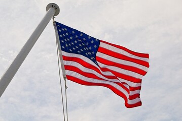 American flag waving in breeze against bright cloudy sky