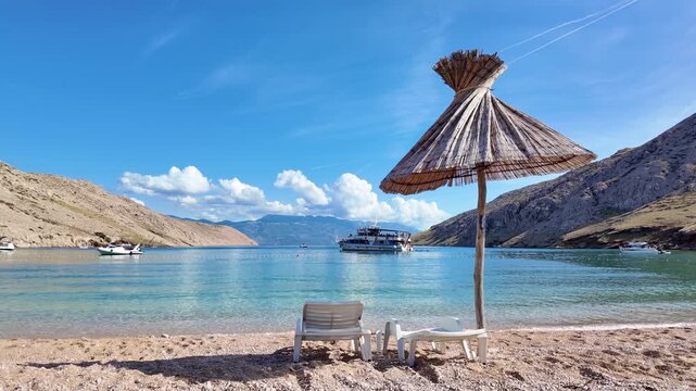 Sandy beach relaxation under a straw parasol with boats and clear blue sky