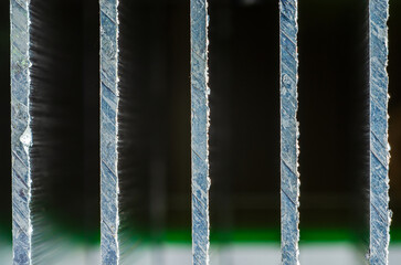 Close-up macro view of rough, textured metal bars with light shining through the gaps