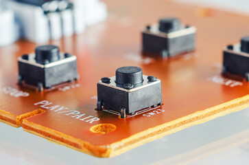 Close-up view of tactile push buttons on a printed circuit board with labels like PLAY/PAIR