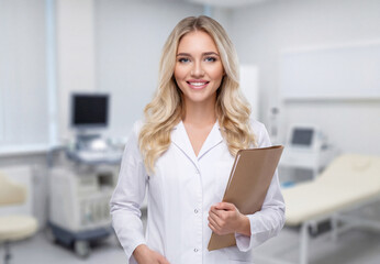 Eine junge &Auml;rztin mit einer Patientenakte l&auml;chelt in der Praxis in die Kamera.