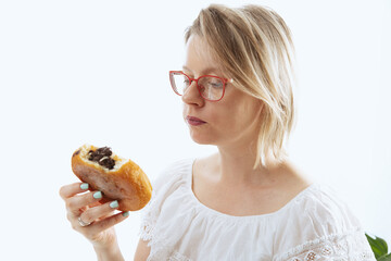 A woman eating a donut with chocolate cream, an unhealthy snack full of sugar and fat