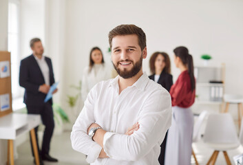 Portrait of a confident serious young bearded business man in white shirt looking cheerful at...
