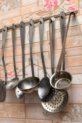 metal ladles and skimmers hanging on the wall