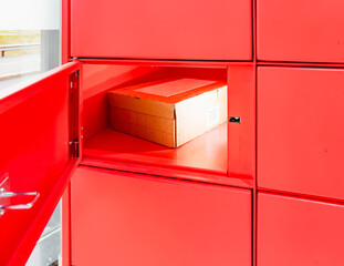 Porsgrunn, Norway - October 20, 2025: Red Instabox parcel locker with an open door revealing a cardboard box inside, showcasing modern delivery solutions and secure package storage