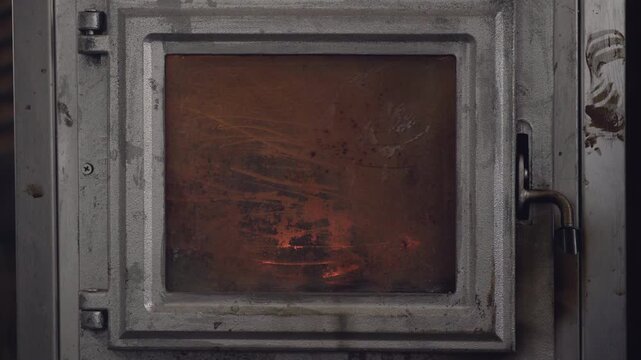 Close-up of burning fire inside an old vintage cast iron wood stove glass door