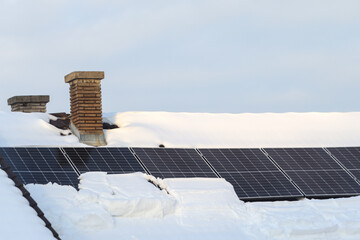 solar panels on house roof covered with heavy snow during winter