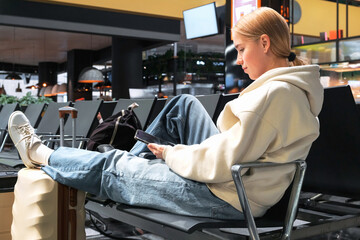 Digital nomad woman using smartphone in modern airport terminal, remote work and solo travel lifestyle,mobile office concept, freelance productivity, location independent work, modern travel routine.