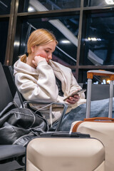 Digital nomad woman using smartphone in modern airport terminal, remote work and solo travel lifestyle,mobile office concept, freelance productivity, location independent work, modern travel routine.