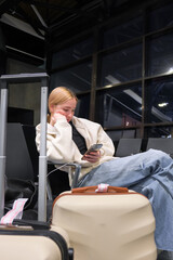 Digital nomad woman using smartphone in modern airport terminal, remote work and solo travel lifestyle,mobile office concept, freelance productivity, location independent work, modern travel routine.