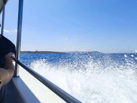 Intense spray of seawater as a boat passes, with the silhouette of St. Mary's Tower on the horizon, Comino MALTA