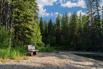 A rustic wooden bench along an Alberta river.