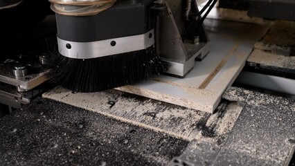 Cnc router machine processing wooden panel with sawdust