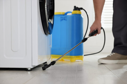 Pest control worker spraying insecticide indoors, closeup