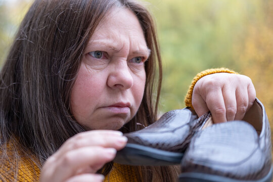 woman sniffing shoes, feeling smell sweaty feet, examining footwear, Unhappy customer customer examining damaged leather shoes, customer rights