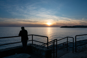 Fototapeta premium Silhouette of man watching Adriatic Sea sunset from promenade