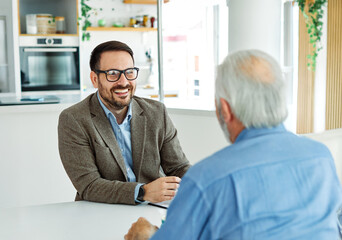 Fototapeta premium Two businessman having a meeting and lookung at a document or a contract agreement in the office, or a senior mad pensioner supported ny a real estate agent or advisor or a doctor. Teamwork and succes