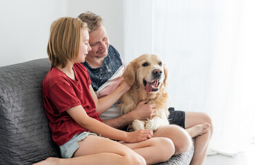 Dad And Little Daughter Pet Golden Retriever Dog On The Sofa, Happy Family At Home