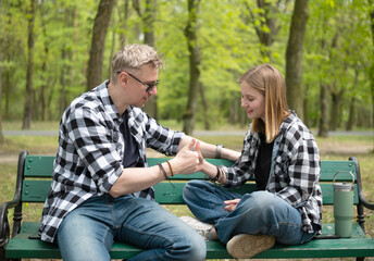 Happy Father And Little Daughter Sitting On A Bench Playing A Thumb War Game In Family Look