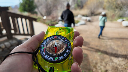 Oak Glen, California, January 6, 2025: A Compass being used on the trail to find direction using the magnetic field of the earth with a needle that points at magnetic north with a bezel to set the dir