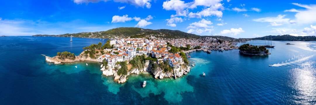 Aerial 3:1 panorama of the old port of Skiathos, Greece. Picturesque harbor with traditional boats and rocky coastline, High Resolution. - Powered by Adobe