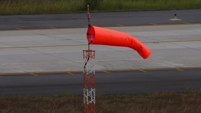 Windsock blow in wind to show speed and direction of wind gusts. Windsock with cloudy sky in the background. Conical tube in fabric used as a basic guide for the direction and speed of the wind.