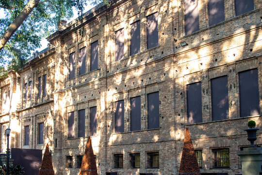 Fachada de edif&iacute;cio hist&oacute;rico em pedra com janelas e sombras de &aacute;rvores