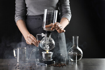 Woman brewing coffee with vacuum coffeemaker at grey table, closeup
