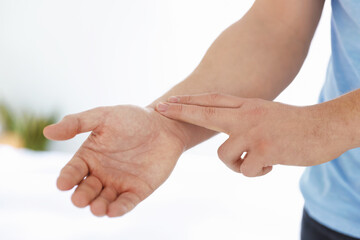 Man checking his pulse with fingers indoors, closeup