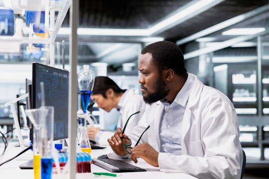 Laboratory scientist squinting eyes at computer monitor, processing DNA patient data for clinical research. Lab specialist unable to believe eyes while looking at genetic analysis diagnostics - Powered by Adobe