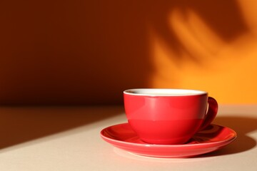Obraz premium Cup of aromatic coffee on beige table near orange wall, space for text
