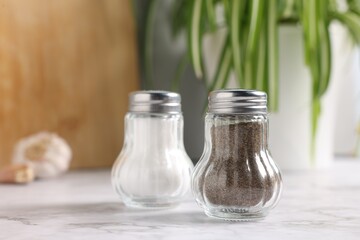 Salt and pepper shakers on white marble table, closeup