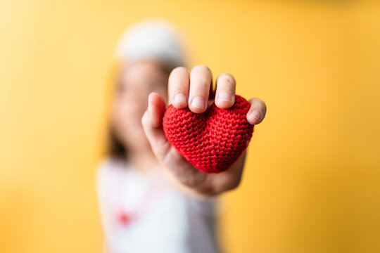 Child plays doctor holding a heart symbol.