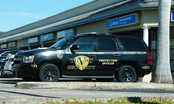 Sarasota, Florida, U.S - Jan 3, 2026 - A black Chevrolet Tahoe patrol vehicle for Trust Security is parked in a lot in front of various offices