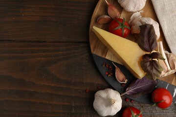 Dairy product. Piece of cheese, tomatoes, basil, peppercorns and garlic on wooden table, flat lay....
