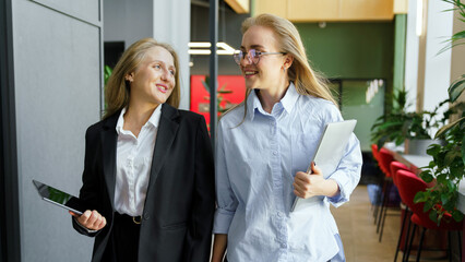 Two women walking in an office space together