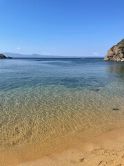 Sunlit Beach with Majestic Cliffs and Deep Blue Sea