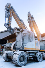 Scenic view frozen hydraulic excavators standing outdoors winter conditions covered snow ice industrial building alpine area. Cold weather impacts machinery operation hydraulic systems reliability