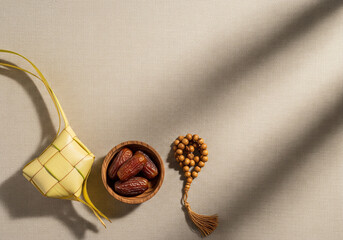 Minimal Ramadan Flat Lay with Ketupat, Dates and Prayer Beads on Fabric Background