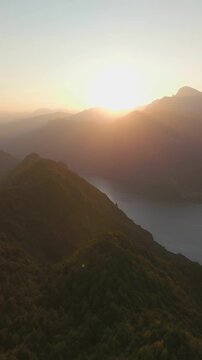Aerial view of Grande Panchina with lake and sunset behind mountains, Capovalle, Italy, vertical video