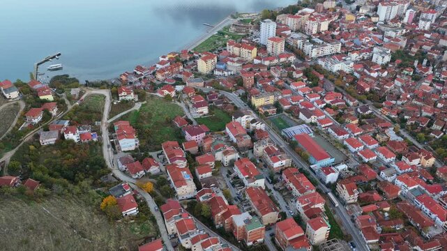 Aerial video of Pogradec, Albania, stretching along the calm shoreline of Lake Ohrid. 