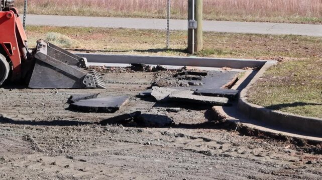 Bulldozers are clearing torn up asphalt from street surface.