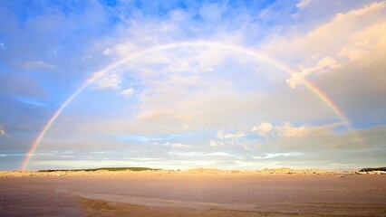 Wonderful rainbow over a area of flat sand beach at Foxton Beach New Zealand