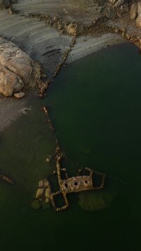 Aerial view above ancient stone structure in lake with rocky landscape, Almendra Reservoir, Spain, vertical video