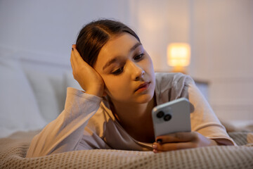 Teenage girl using smartphone on bed at home