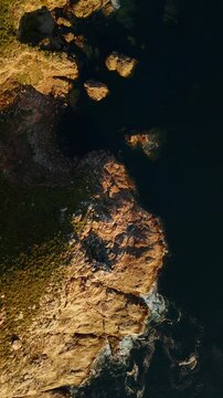 Birds eye view above cliff and ocean rocks with waves, Fisterra, Spain, vertical video
