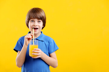 Boy with glass of fresh orange juice on yellow background. Space for text